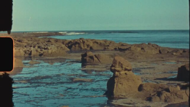 Super 8 vintage film of rock pool boulders and waves breaking on headland reef ocean coastline of Broulee beach town in South Coast Australia light leaks burn
