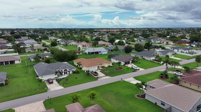 Suburban neighborhood in Florida. Green lawns and driveways add to the residential charm. Quiet community layout with spacious yards and well-kept homes. Aerial.