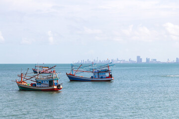 Fishing boat floating on the sea with city on background.