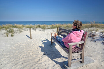 person sitting on a bench with a view to the beach