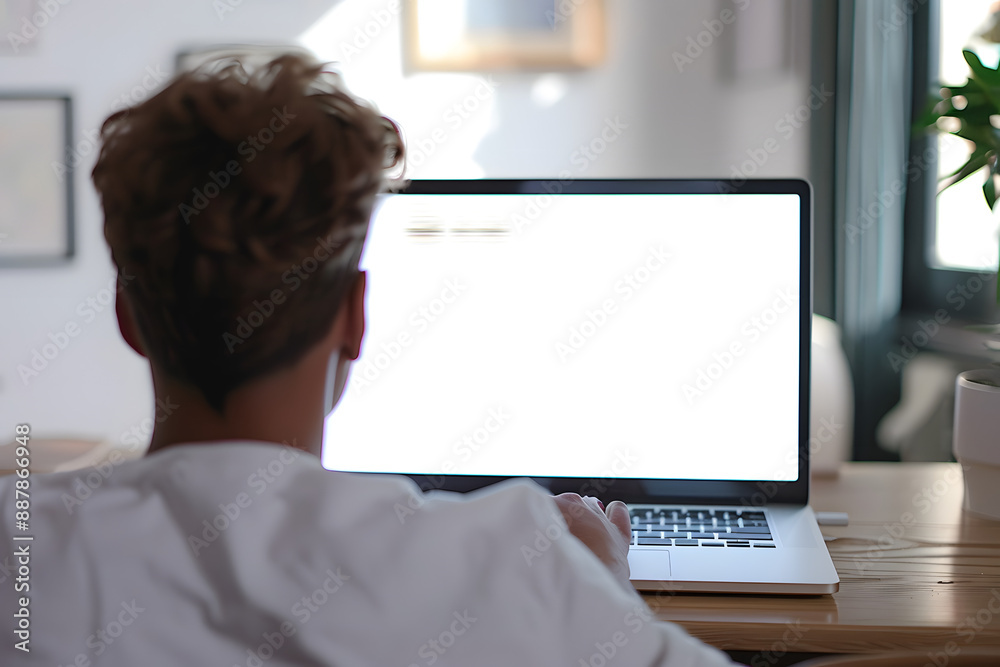 Sticker Over shoulder shot of a young man using computer laptop in front of an blank white computer screen in home