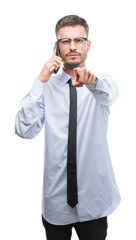 Young business adult man talking on the phone pointing with finger to the camera and to you, hand sign, positive and confident gesture from the front