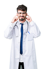 Fototapeta premium Young doctor man wearing hospital coat over isolated background covering ears with fingers with annoyed expression for the noise of loud music. Deaf concept.