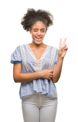 Young afro american woman over isolated background smiling with happy face winking at the camera doing victory sign. Number two.