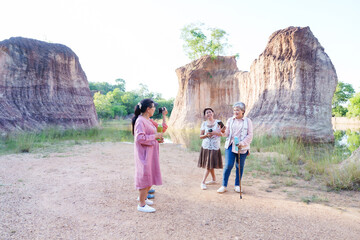 Elderly Asian women traveling and exploring a scenic rocky area. Dressed casually, holding water bottles, enjoying the sunny day, surrounded by nature, having a conversation, reflecting friendship