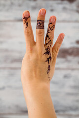 Henna tattoo design on a finger with a wooden background providing a glimpse into the intricate and...