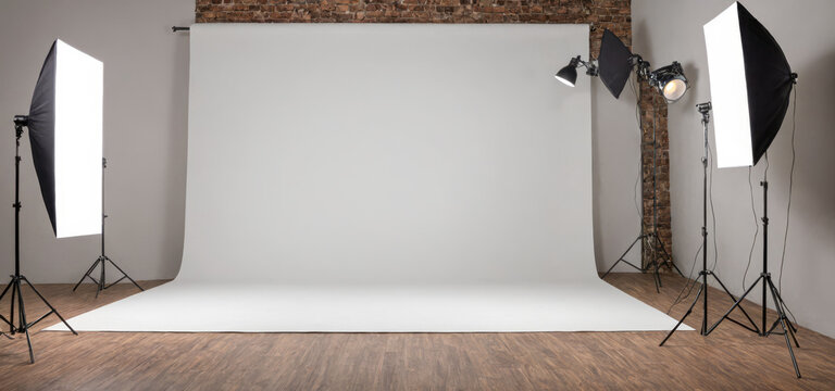 Professional photography studio setup with lighting equipment, soft box, backdrop stand, white seamless paper roll in indoor brick wall room for photo shoots