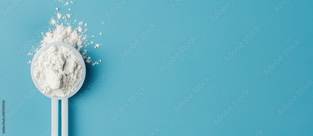 Poster White powder in a plastic spoon arranged on a blue background in a composition ideal for adding text suitable for display with copy space image