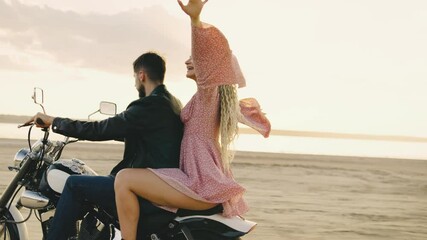 An adventurous couple cherishing a motorcycle ride along the beach, embracing the happiness of a carefree moment together at sunset, enjoying the freedom and scenic beauty of the sea breeze
