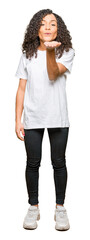 Fototapeta premium Young beautiful woman with curly hair wearing white t-shirt looking at the camera blowing a kiss with hand on air being lovely and sexy. Love expression.