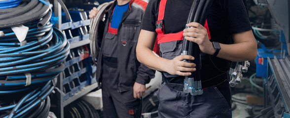 Industrial worker hold hydraulic hose on background machine with metal fitting