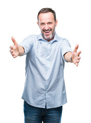 Middle age hoary senior business man over isolated background looking at the camera smiling with open arms for hug. Cheerful expression embracing happiness.