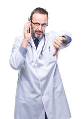 Middle age senior hoary doctor man talking on smartphone over isolated background with angry face, negative sign showing dislike with thumbs down, rejection concept
