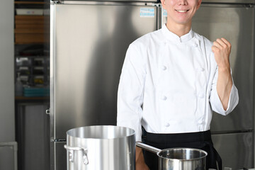 調理場でガッツポーズをする若い男性調理師