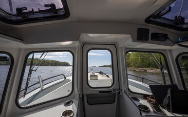 Inside a modern boat on a calm lake, sunlight beams in through an open hatch, highlighting the sleek design. The boat gently rocks, creating a peaceful journey.