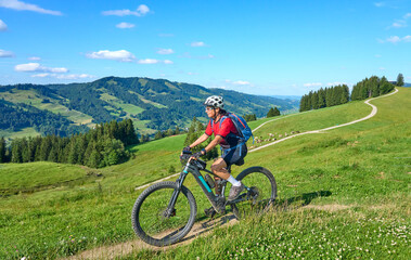 nice active senior woman riding her electric mountain bike at Mount Huendle in Oberstaufen, Allgaeu Alps , Bavaria, Germany