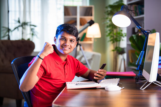 ndian Asian teenage student learning online with computer, headphones, and smartphone