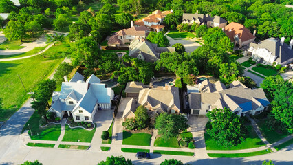 Suburban park lush green trees, concrete walking path in wealthy residential neighborhood with large mansion houses, swimming pool, concrete roof tiles, Dallas Fort Worth metroplex, aerial view