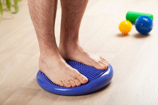 man doing flatfoot correction gymnastic exercise balancing on massage cushion at home