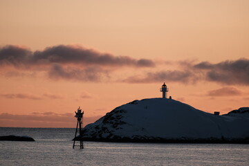 Sunset Silhouette of Lighthouse on Snowy Hill