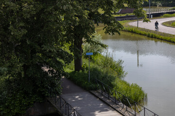 Fototapeta premium Outdoor summer canal moat forest pathway beautifully illuminated with a side light. Walking season background concept.