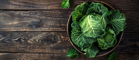 Fototapeta premium Top down view of a wooden background with a bowl filled with savoy cabbage creating an ideal copy space image