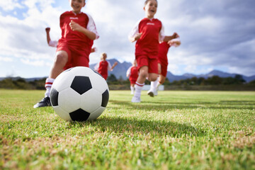 Running, closeup and sports with children and soccer ball on field for training, competition and fitness. Teamwork, summer and action with football player on pitch for goals, energy and kids game