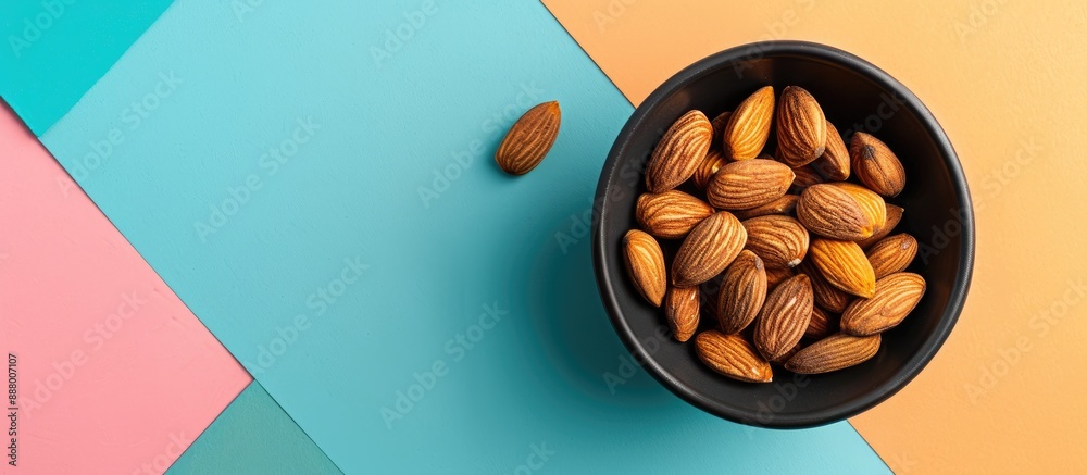 Wall mural A bowl with almonds set on a colorful backdrop with room for a message in the picture. Copy space image. Place for adding text and design