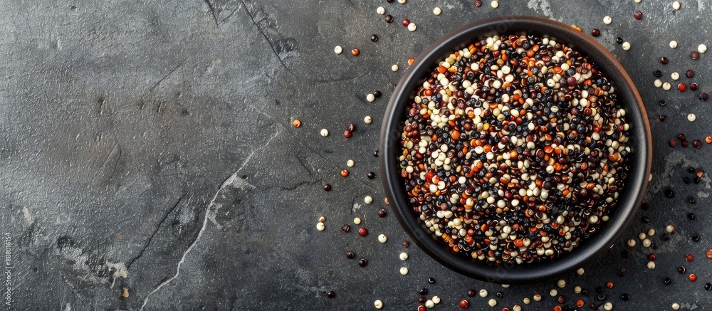 Sticker Top view of a bowl containing red white and brown quinoa seeds on a gray stone backdrop with room for text or images. Copy space image. Place for adding text and design