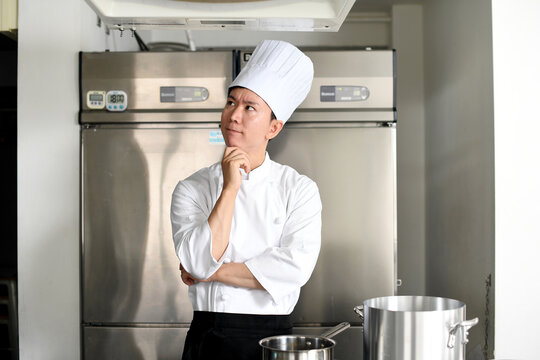 調理場で考える若い調理師のアジア人男性