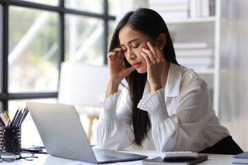 A woman in the office is stressed and has a headache from overwork. Tired business woman sleepy and...