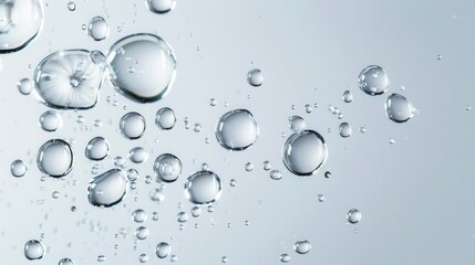 The transparent gel serum drops on a gray background are surrounded by water drops
