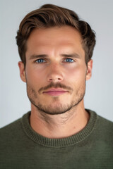 Fototapeta premium portrait of a man with brown hair and stubble against a white background