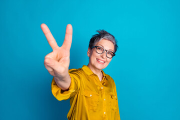 Photo of charming positive woman wear blouse eyeglasses showing you v-sign empty space isolated blue color background
