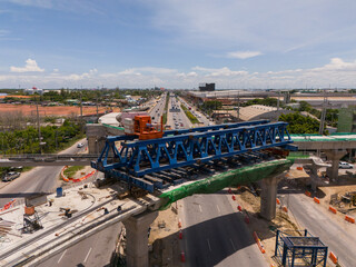 Fototapeta premium From above, witness the vibrant hustle of a modern tropical Asian traffic junction, where roads intersect amidst a dynamic flow of vehicles, creating a kinetic mosaic of urban movement.