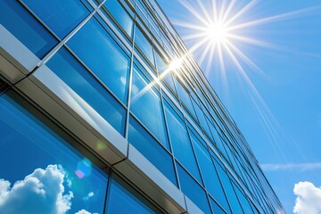 Modern glass building with sunburst reflection on windows and blue sky