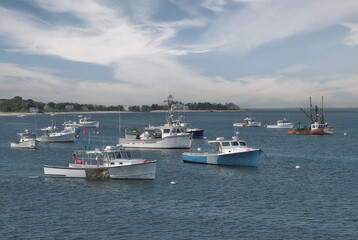 Fototapeta premium Beautiful summer day on Cape Cod. Several fishing boats anchored in quiet harbor viewed from observation deck at Chatham Fish Pier.