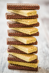 Stacked chocolate and vanilla wafers showing their layers and textures on a rustic wooden surface.