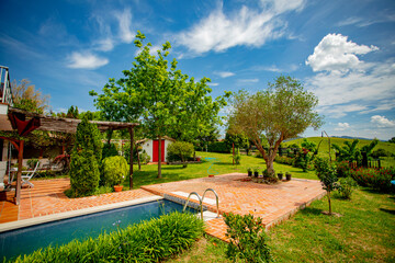 Fototapeta premium Modern luxury villa with swimming pool and relaxation areas, surrounded by trees and plants.