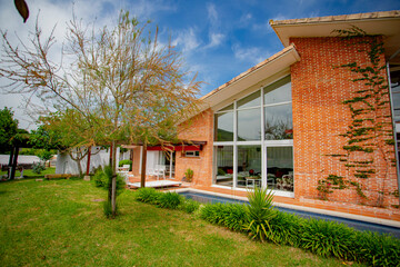 Modern luxury villa with swimming pool and relaxation areas, surrounded by trees and plants.