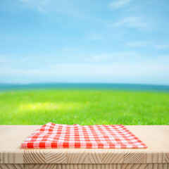 beautiful nature with fabric cloth or placemat on wood table top on blur green field and sea beach