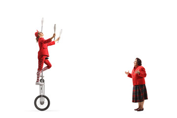 Amuzed elderly woman watching an acrobat riding a giraffe unicycle and juggling © Ljupco Smokovski