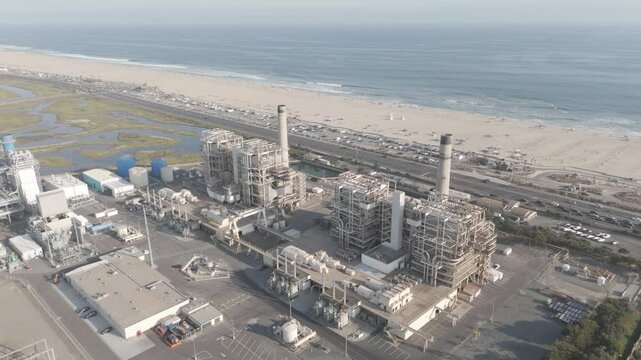 Drone pullout shot of AES Huntington Beach on a sunny day near the sea in California, United States