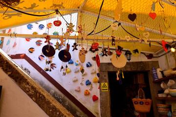 Colorful handmade goods in the souvenir shop; colorful porcelain, clay, and ceramic products; kitchen utensils; vases; jugs; knitted baskets; plates on the wall; pigs; cacti; Halloween