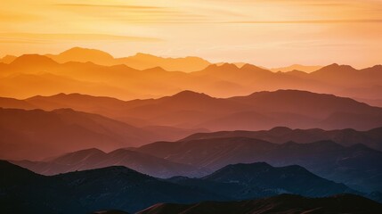 Wide shot of a mountain range at sunset, bathed in warm hues.
