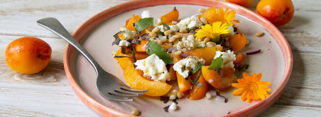 plate with salad with nectarines and feta cheese on the table