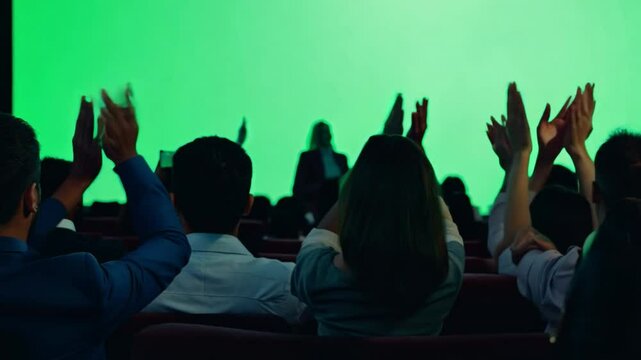 Happy audience clapping their hands, looking at the green-keyed movie screen.