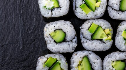 Top view of fresh vegetarian sushi rolls with cucumber and avocado, beautifully arranged on a dark slate background.