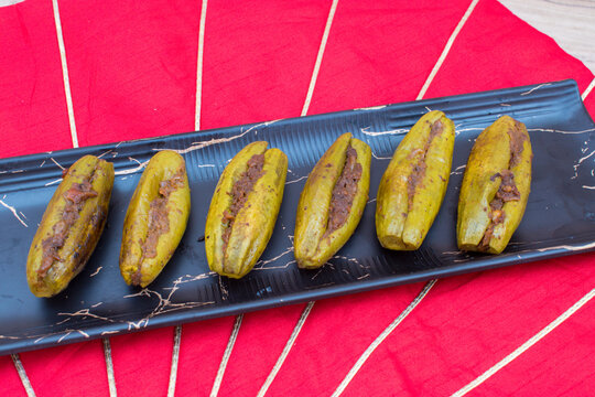 Bharwa Parwal or Stuffed Pointed Gourd in black plate with red background . 