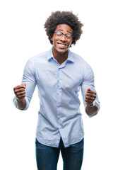 Afro american business man wearing glasses over isolated background very happy and excited doing winner gesture with arms raised, smiling and screaming for success. Celebration concept.